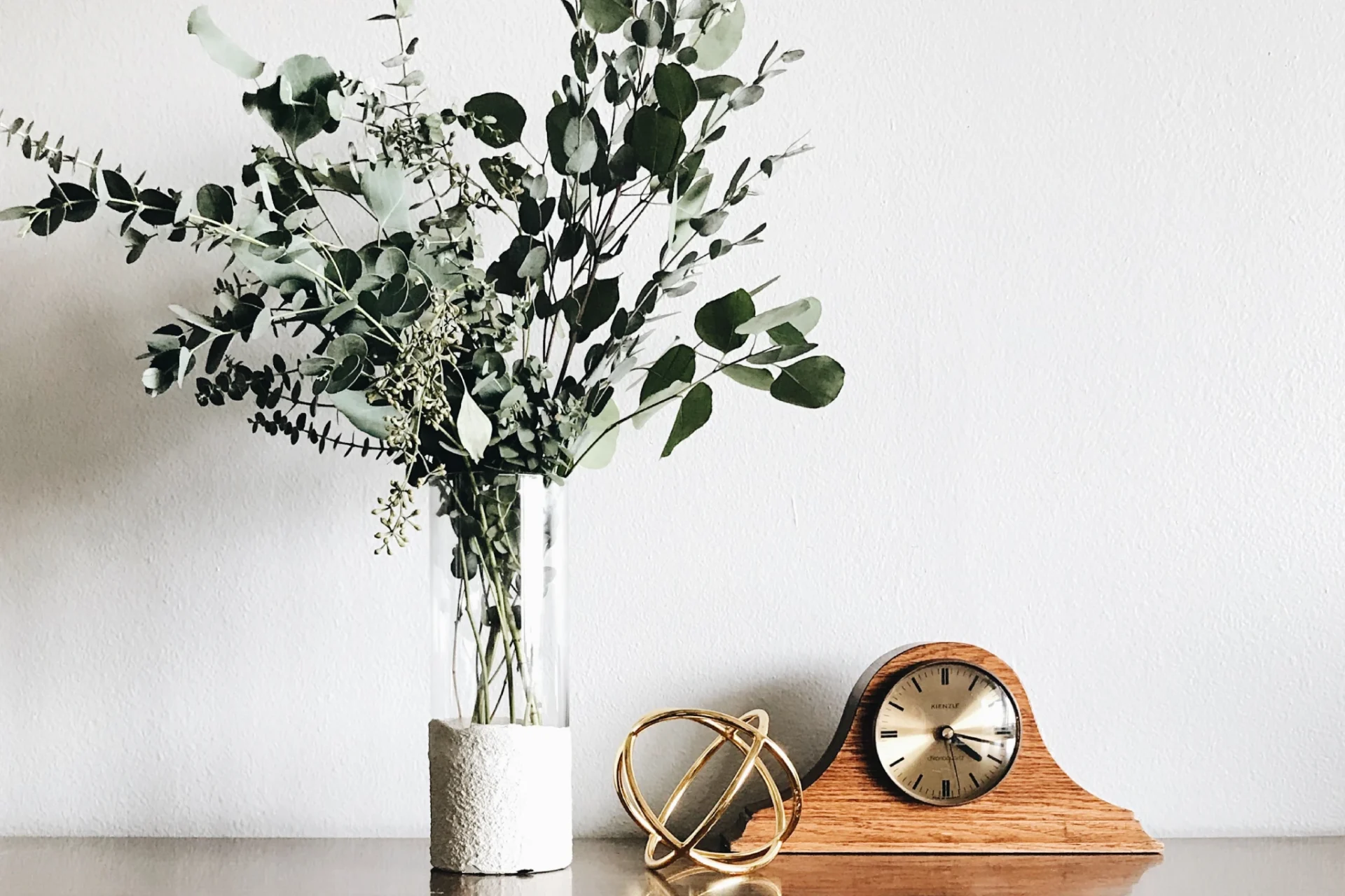 A vase with flowers in it next to a clock.